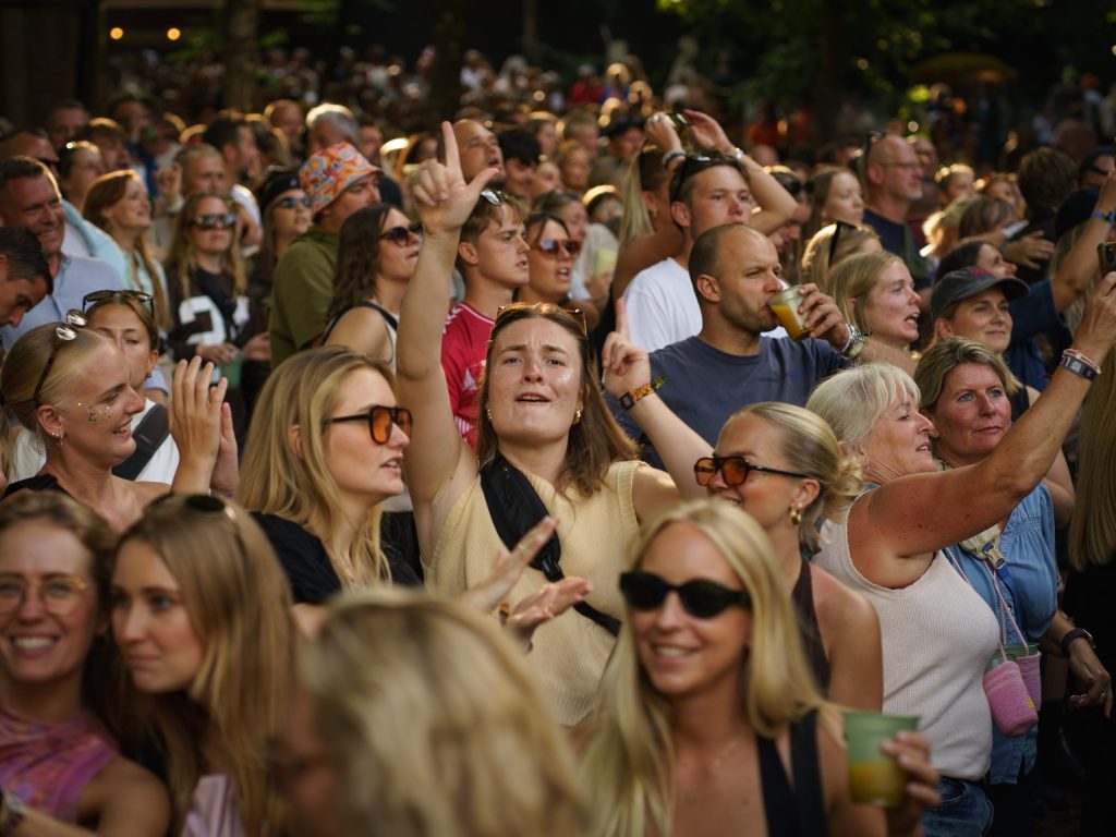 Mennesker fester på SMUKFEST 2025. Kvinde synger med