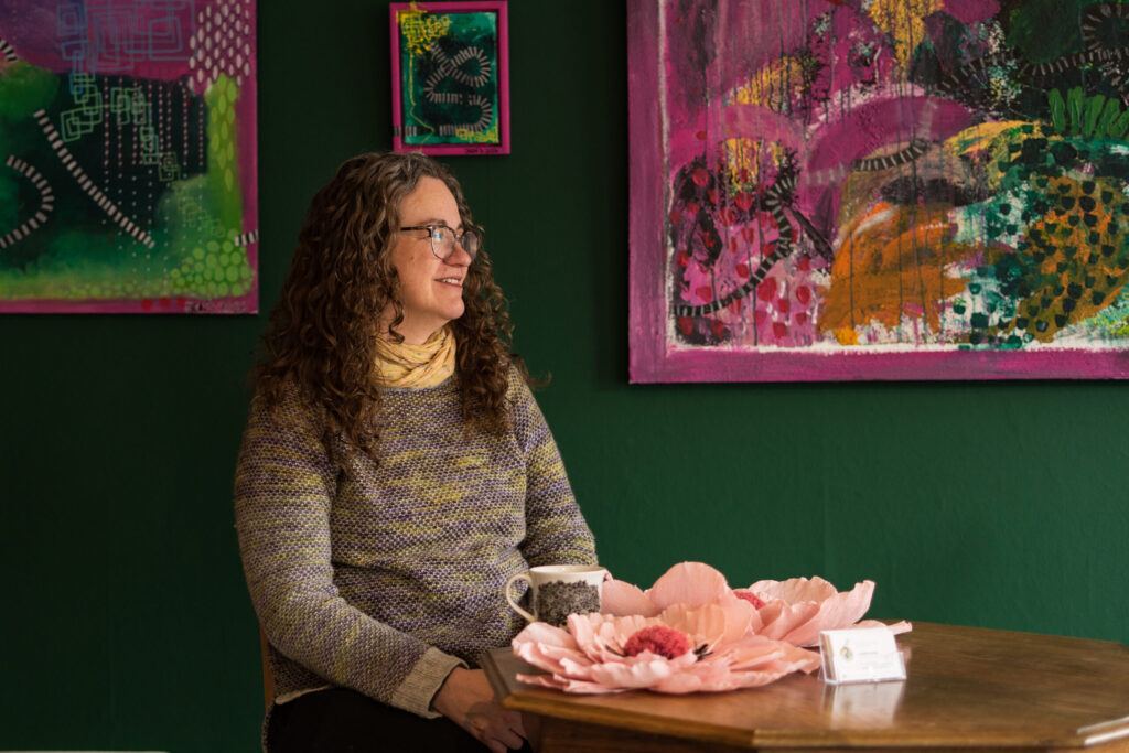 Charlotte Virkelyst sidder i hendes butik ved et bord og kigger ud mod gaden